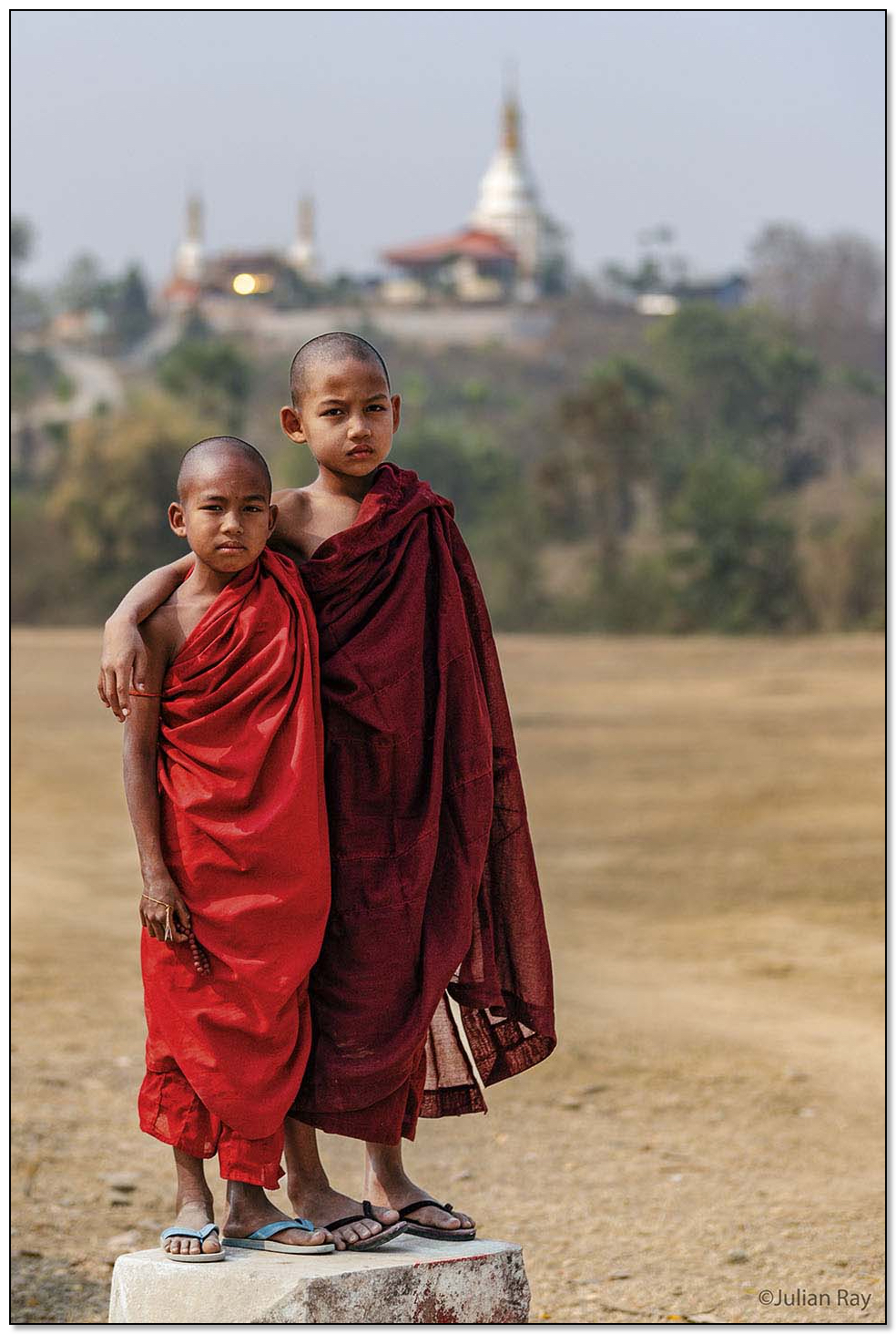 Two young monks arm and arm infront of a pagoda
